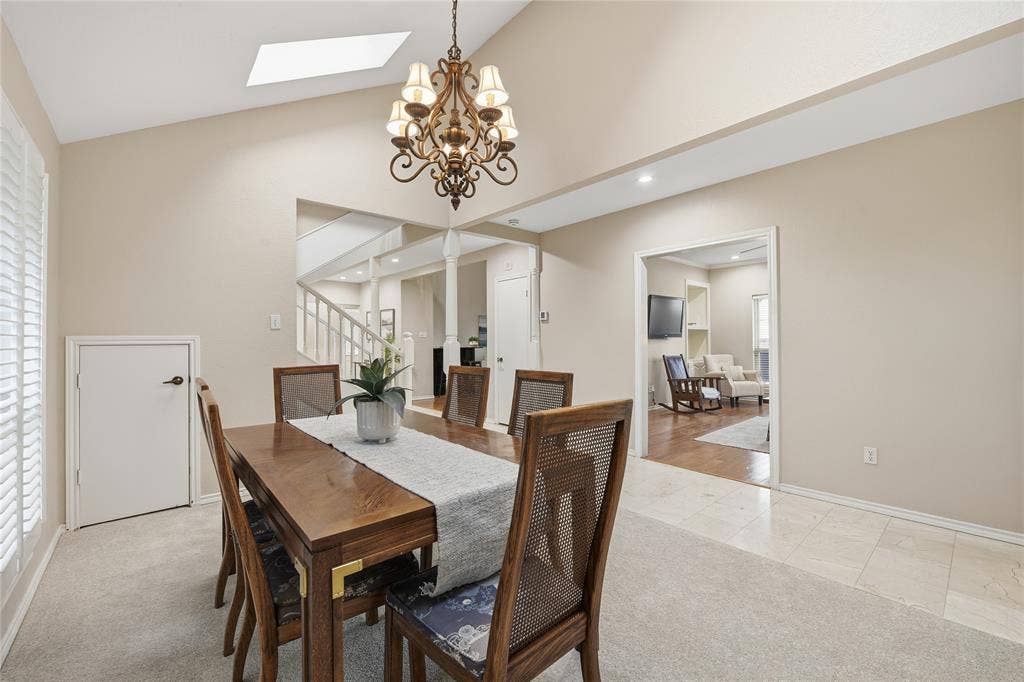 4424 Westridge Avenue, Fort Worth, TX 76116 Vaulted ceiling with skylight, ornate chandelier, plantation shutters, and a mixture of carpet and tile flooring