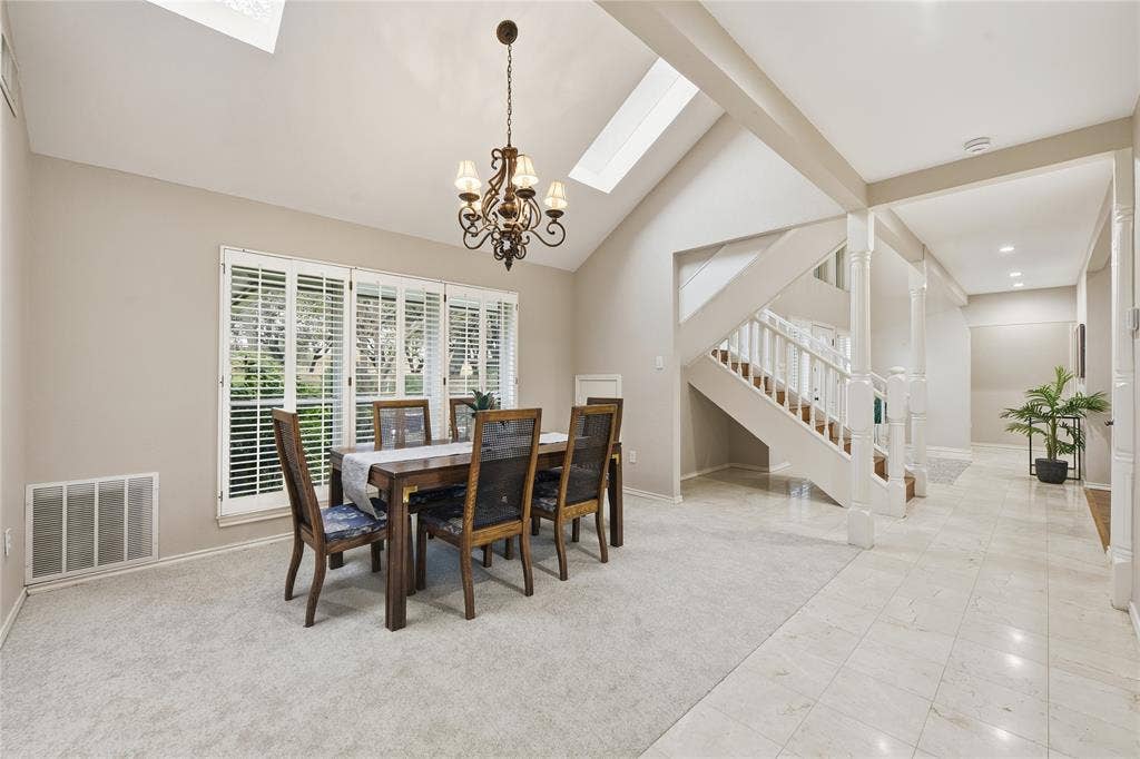 4424 Westridge Avenue, Fort Worth, TX 76116 Vaulted ceiling with skylights, chandelier, white plantation shutters, staircase with wood-finish treads, and tile flooring