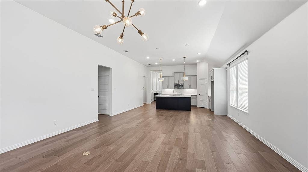 3129 Grayslick Avenue, Celina, TX 75009 Wood-finish flooring, recessed lighting, and a modern chandelier illuminate this open-concept space