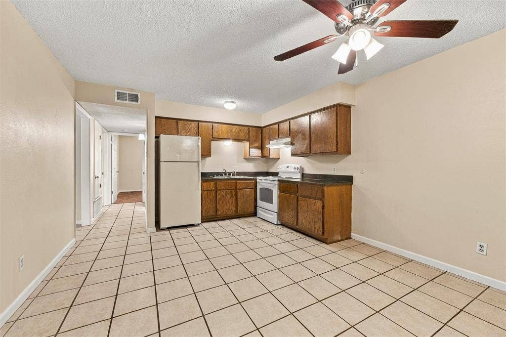 410 W Franklin Street, #5, Waxahachie, TX 75165 Kitchen area featuring wood-finish cabinetry, white appliances, and a ceiling fan with integrated lighting
