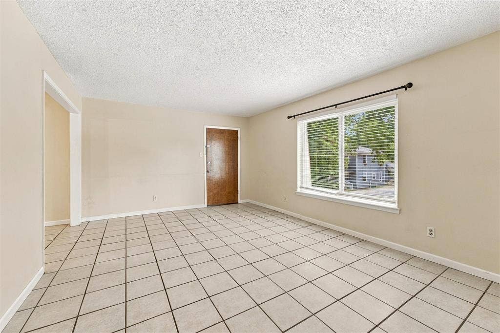 410 W Franklin Street, #5, Waxahachie, TX 75165 Spacious room featuring tile flooring, neutral wall tones, a large window, and a wood-finish entry door