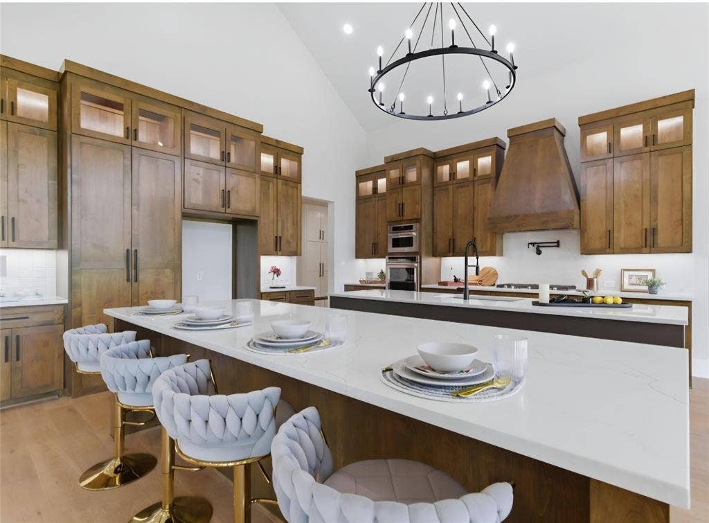 2608 Southbay, Northlake, TX 76226 Vaulted ceiling with a large circular chandelier, wood-finish cabinetry, built-in double ovens, white countertops, and wood-finish flooring