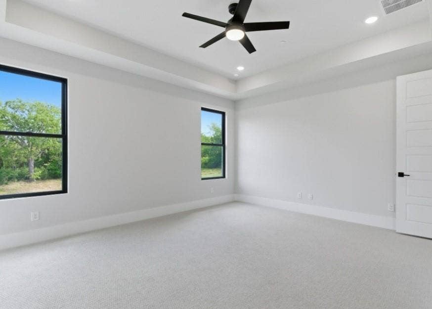 2608 Southbay, Northlake, TX 76226 Recessed lighting, ceiling fan, tray ceiling, two large windows with black trim, and light-colored carpeting