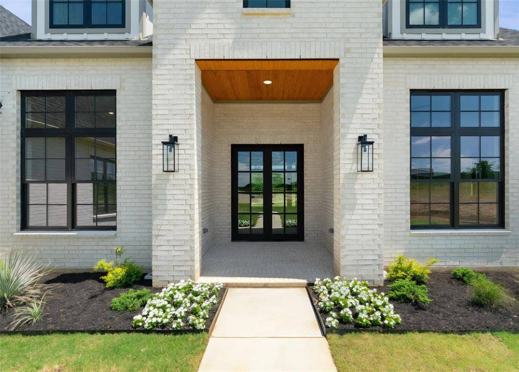 2608 Southbay, Northlake, TX 76226 White brick exterior featuring a recessed entry, wood-finish ceiling, double glass-paneled doors, and black grid-pattern windows