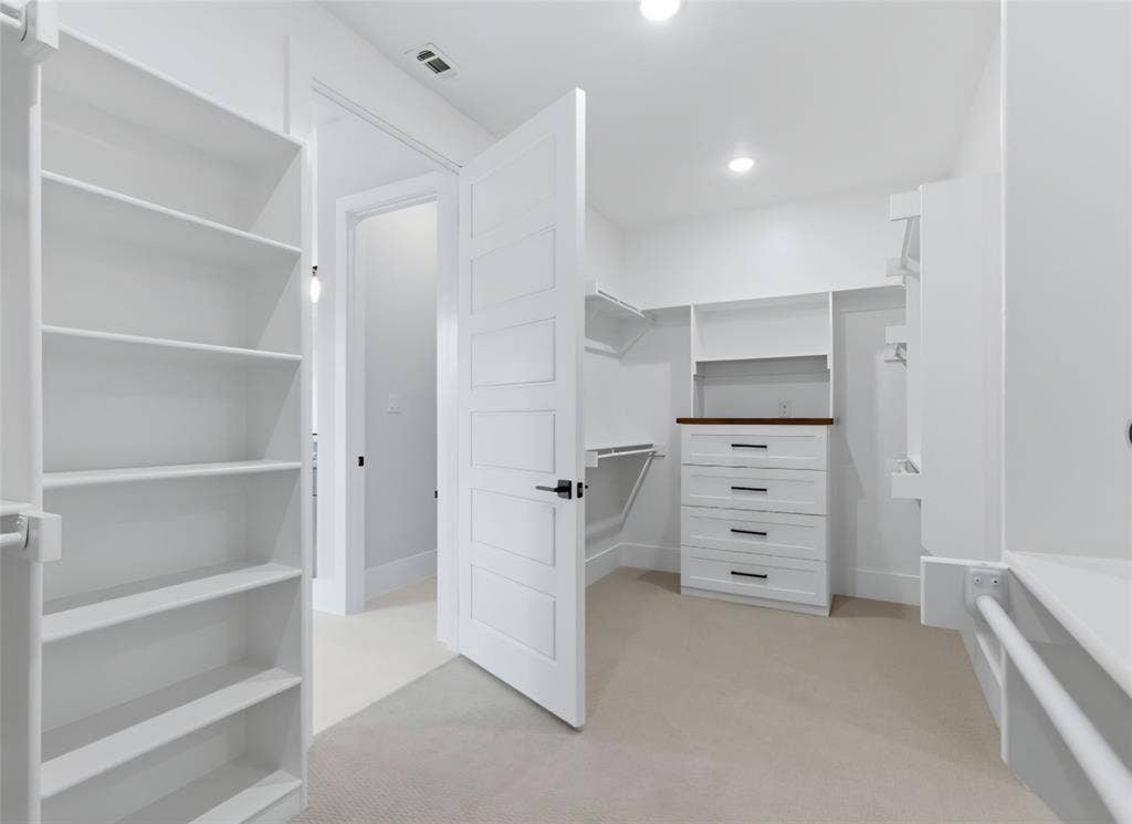 2608 Southbay, Northlake, TX 76226 Custom closet system featuring built-in shelving, integrated drawers with dark hardware, and carpet flooring
