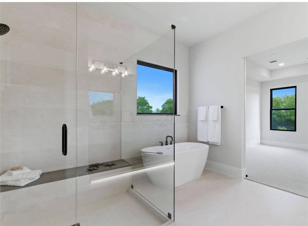 2608 Southbay, Northlake, TX 76226 Freestanding soaking tub, glass-enclosed shower with tiled walls, built-in shower bench, and contemporary vanity lighting