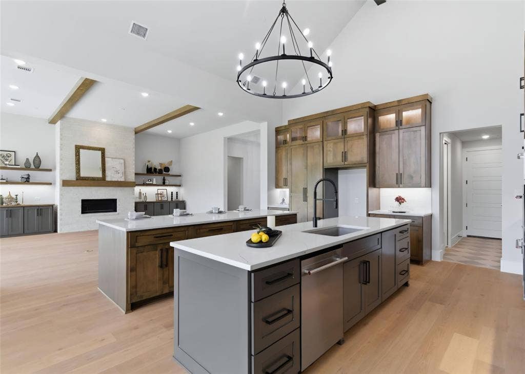 2608 Southbay, Northlake, TX 76226 Vaulted ceiling with exposed wood beams, dual kitchen islands with light countertops, built-in electric fireplace, and wood-finish flooring