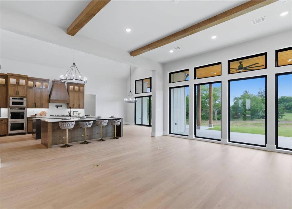 2608 Southbay, Northlake, TX 76226 Expansive open-concept living space with wood-finish flooring, exposed ceiling beams, and a modern kitchen featuring wood cabinetry