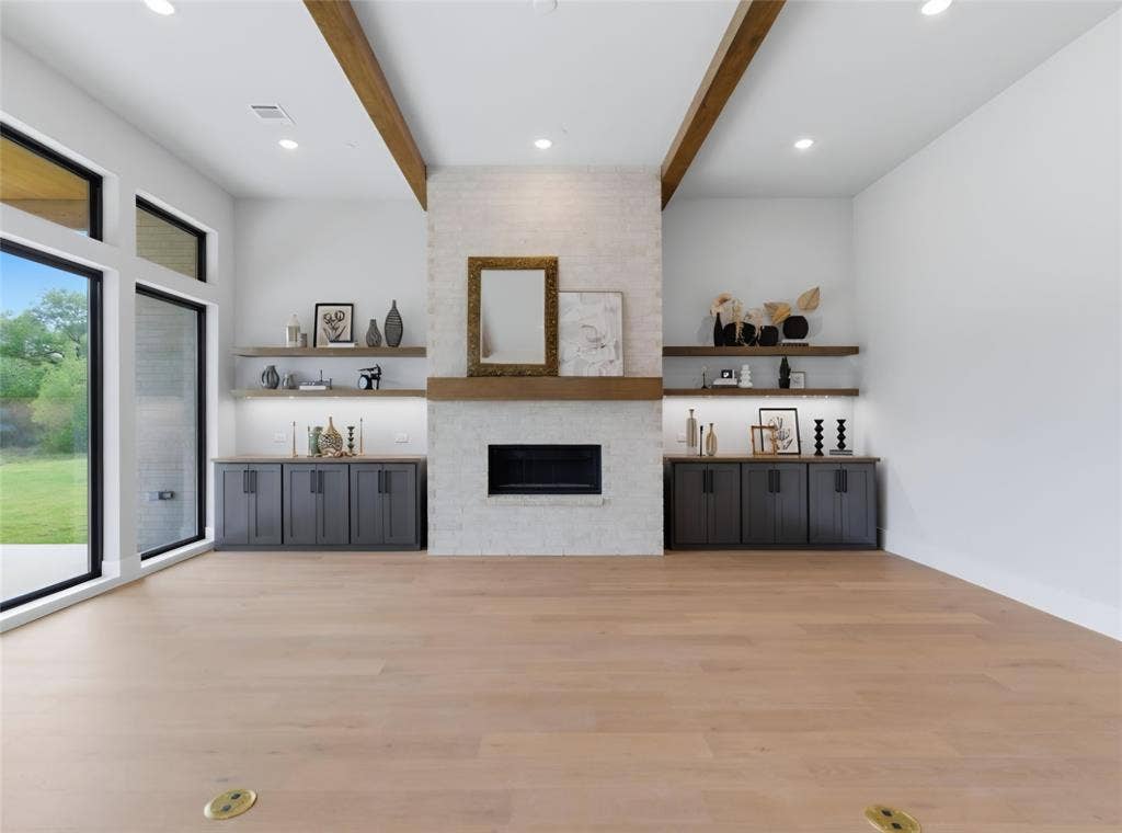 2608 Southbay, Northlake, TX 76226 Expansive living area featuring light wood-finish flooring, a white brick fireplace with a wood mantel, built-in cabinetry, and large windows