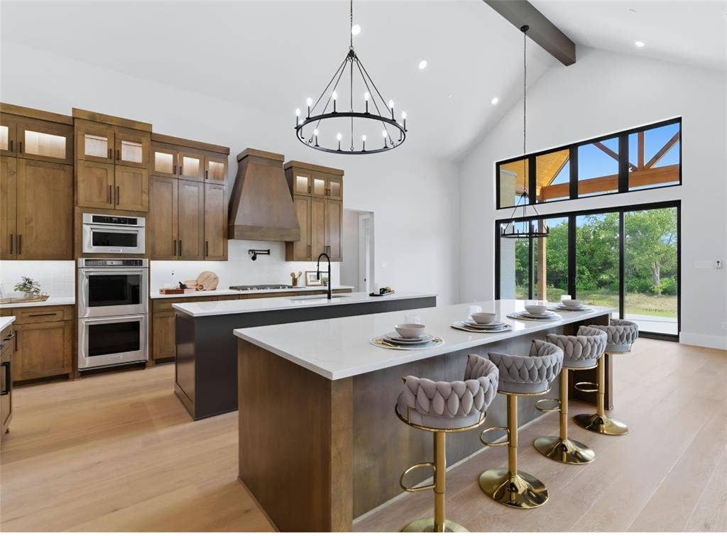 2608 Southbay, Northlake, TX 76226 Vaulted ceiling with an exposed beam, light wood-finish flooring, full-height cabinetry with integrated appliances, kitchen island with a white countertop, and expansive glass doors
