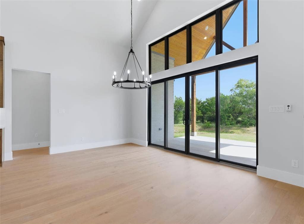 2608 Southbay, Northlake, TX 76226 Vaulted ceiling with wood paneling, wood-finish flooring, black chandelier, and multi-panel sliding glass doors