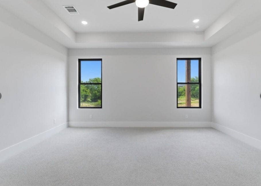 2608 Southbay, Northlake, TX 76226 Recessed lighting and a ceiling fan illuminate this carpeted room, featuring two tall windows with dark frames and a tray ceiling