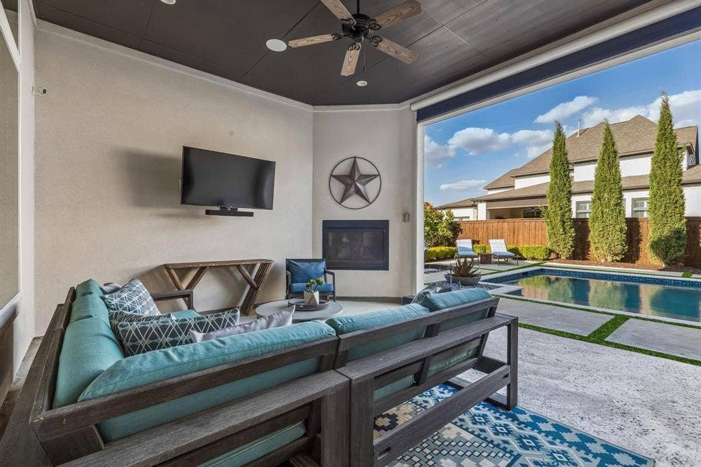 7342 Shoestring Drive, Frisco, TX 75036 Covered outdoor living area with a fireplace and electric retractable screens for year-round comfort and entertaining.