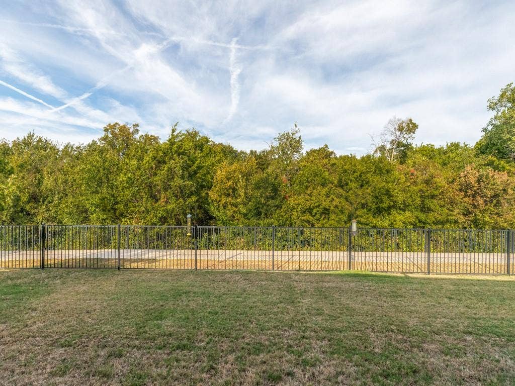 Expansive backyard featuring a manicured lawn and black metal fencing