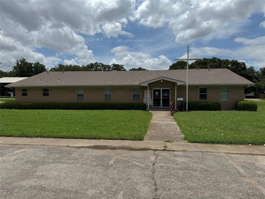 2801 Elm Street, Denton, TX 76201 Brick exterior building featuring a covered entry, multiple windows, and a paved parking area