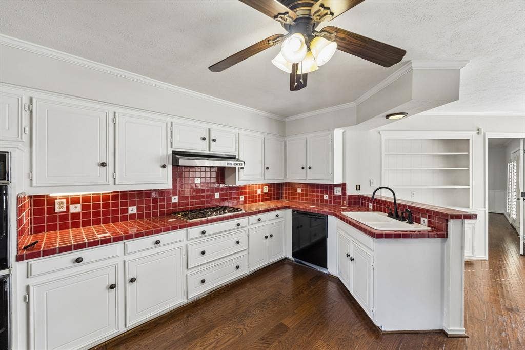 10322 White Rock Place, Dallas, TX 75238 Spacious kitchen featuring white cabinetry with black hardware, red tile backsplash, hardwood flooring, and ample counter space across an L-shaped layout