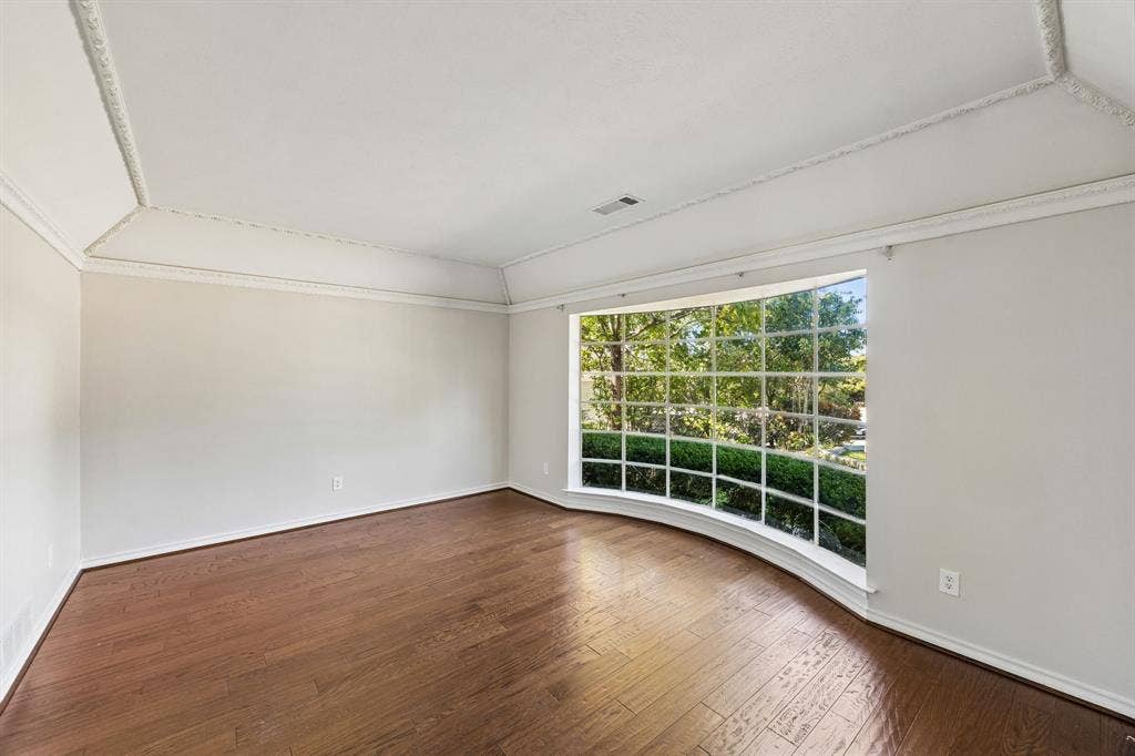 10322 White Rock Place, Dallas, TX 75238 Second living room showcasing hardwood flooring, freshly painted walls, and an expansive multi-pane window wall with natural light and outdoor scenery. This room is also a perfect in-home office.