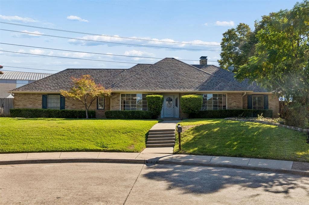 10322 White Rock Place, Dallas, TX 75238 Charming brick ranch featuring a sweeping front lawn with mature landscaping, a welcoming covered entry with stepped walkway