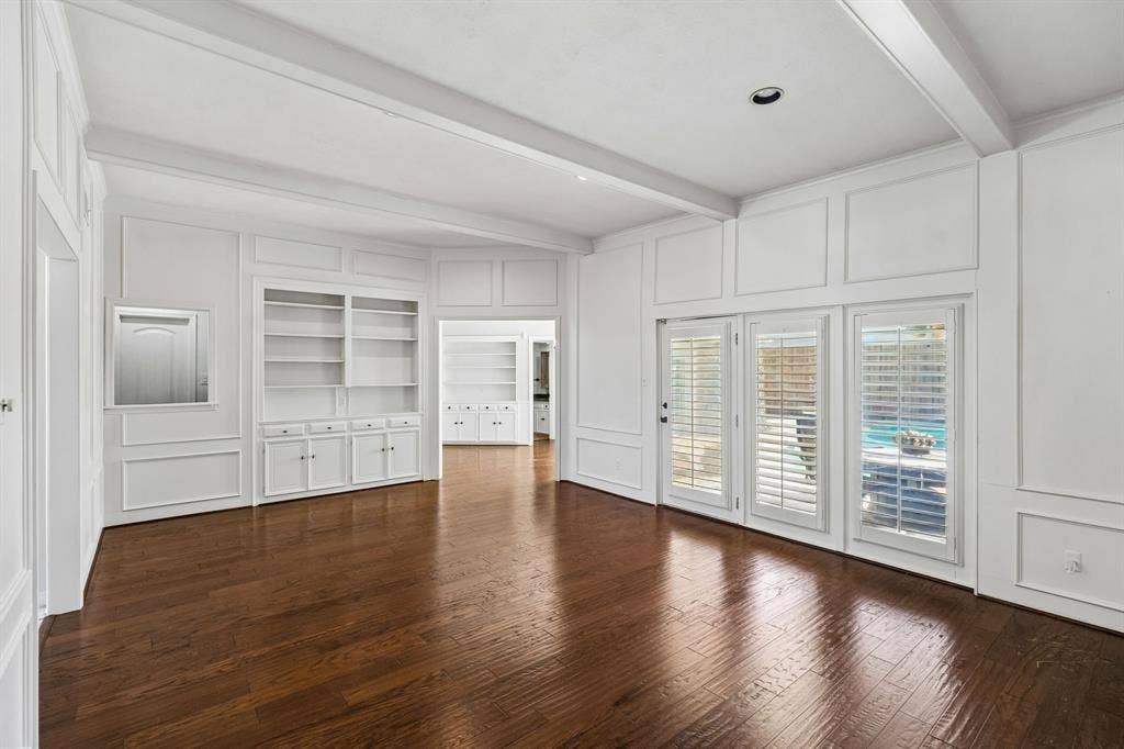 10322 White Rock Place, Dallas, TX 75238 Elegant main living room showcasing hardwood flooring, custom built-in cabinetry with multiple storage drawers and cabinet doors, and an abundance of natural light