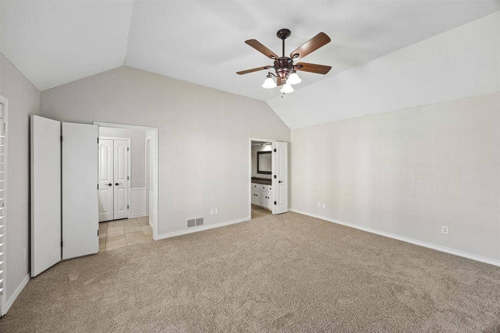 10322 White Rock Place, Dallas, TX 75238 Spacious primary bedroom featuring vaulted ceilings, new carpet, and ensuite bath with separate vanities.