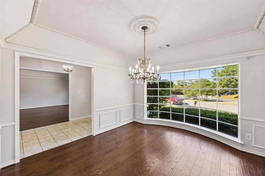 10322 White Rock Place, Dallas, TX 75238 Formal dining room features hardwood flooring, chandelier lighting, decorative ceiling molding, wainscoting, and bay window providing lots of natural light