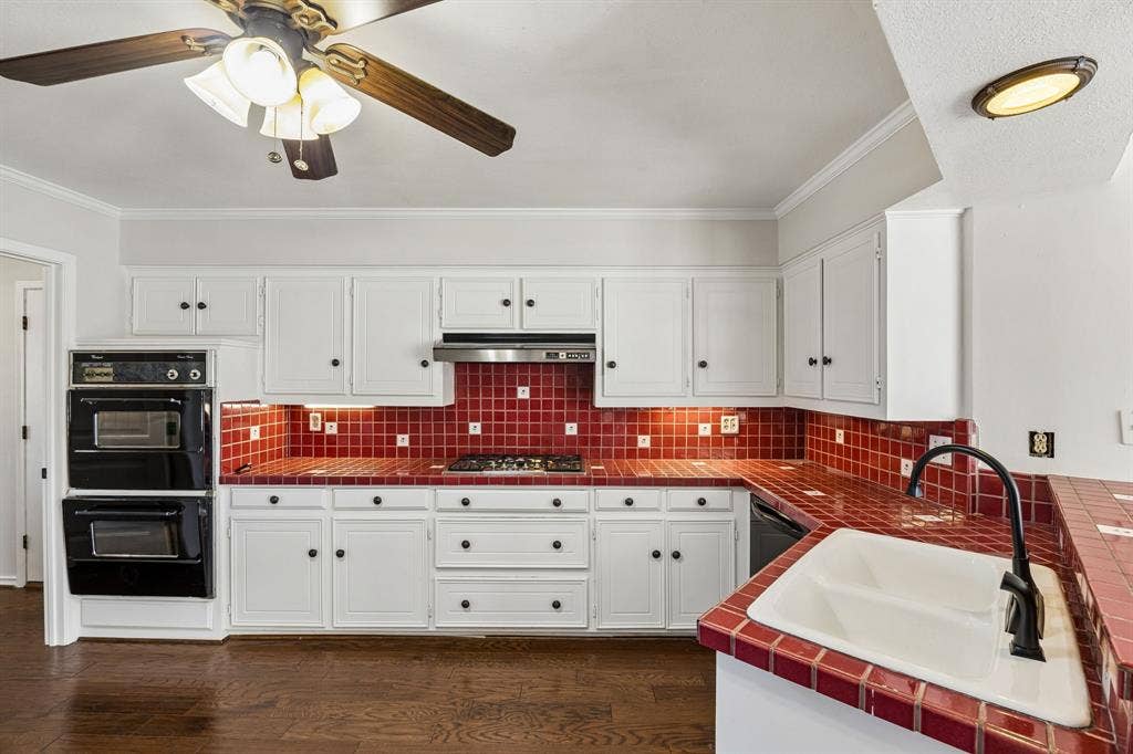 10322 White Rock Place, Dallas, TX 75238 Kitchen featuring white cabinetry, red tile countertops, red tile backsplash, double wall ovens, with laundry room off to the side