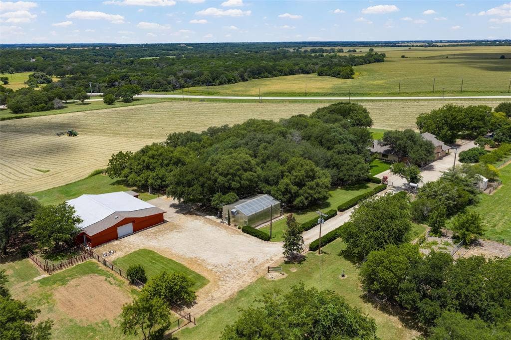 2029 Speegleville Road, Woodway, TX 76712 Expansive property featuring a red barn with a metal roof, a greenhouse, a gravel driveway, and mature landscaping