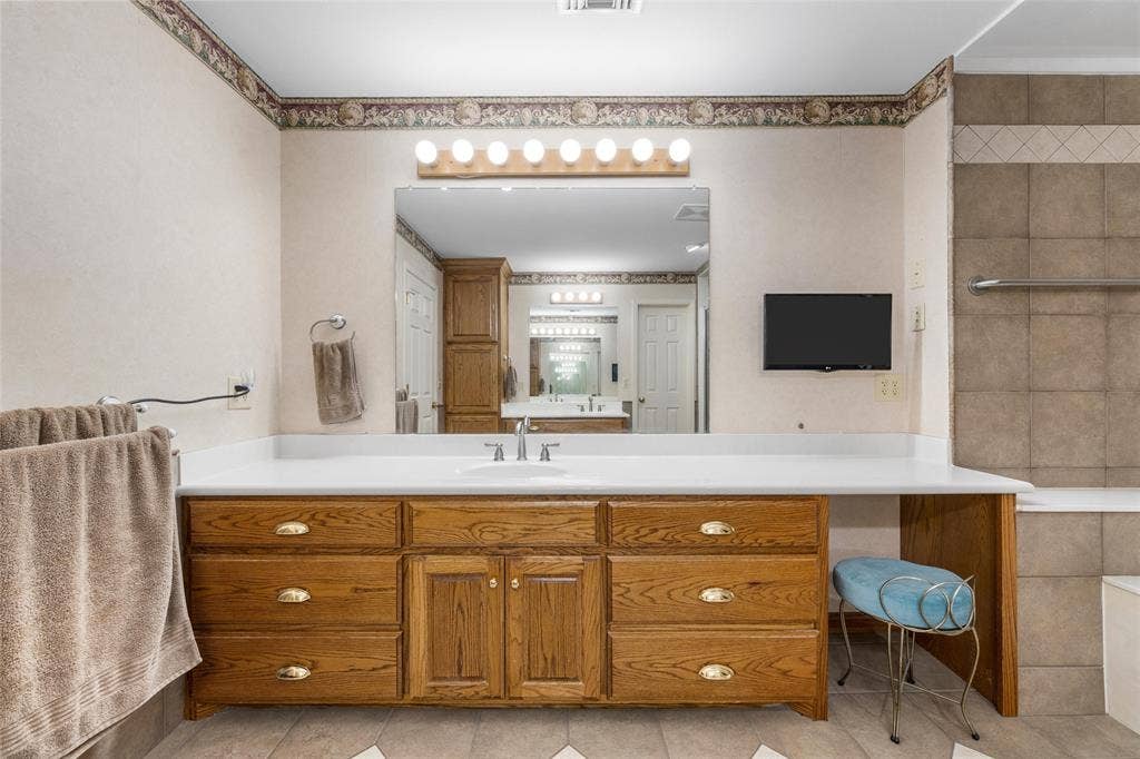 2029 Speegleville Road, Woodway, TX 76712 Wood-finish vanity with multiple drawers, white countertop, and integrated sink