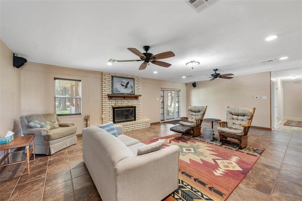 2029 Speegleville Road, Woodway, TX 76712 Spacious room featuring tile flooring, a brick fireplace with a wood mantle, and multiple ceiling fans