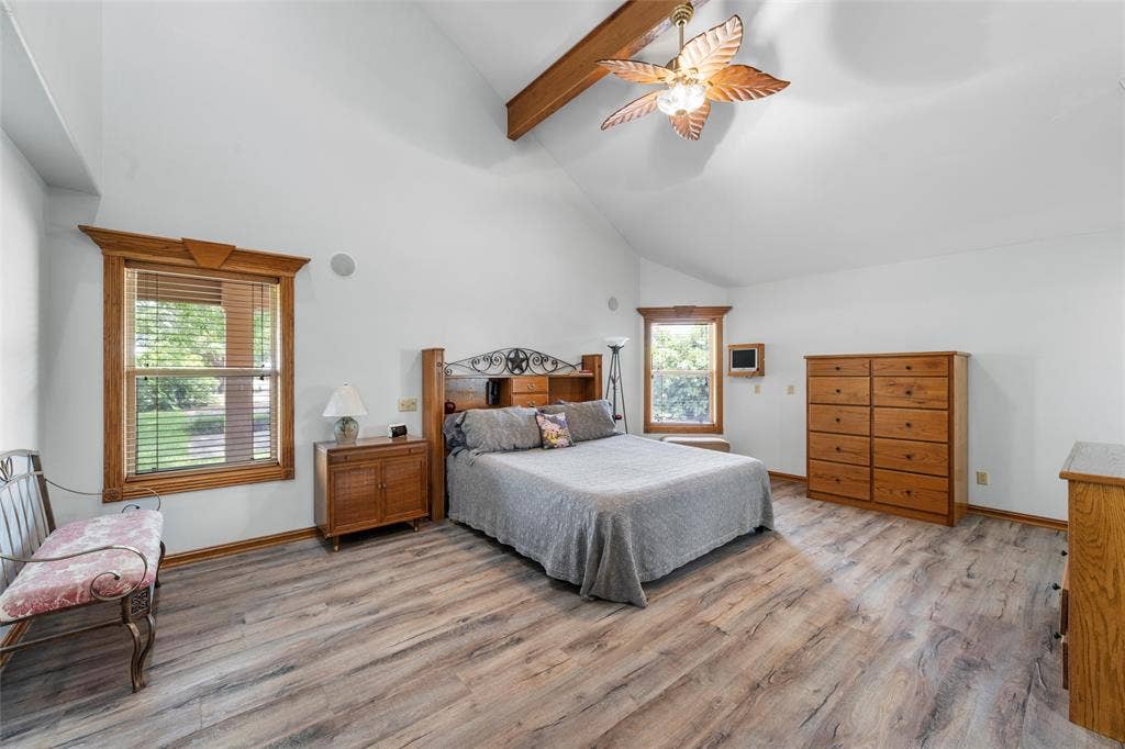 2029 Speegleville Road, Woodway, TX 76712 Spacious primary bedroom suite featuring vaulted ceilings with exposed wooden beams, wood-finish flooring throughout, and abundant natural light from multiple windows