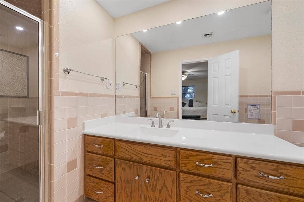 2029 Speegleville Road, Woodway, TX 76712 Wood-finish vanity with ample storage, large vanity mirror, recessed lighting, and a glass-enclosed shower