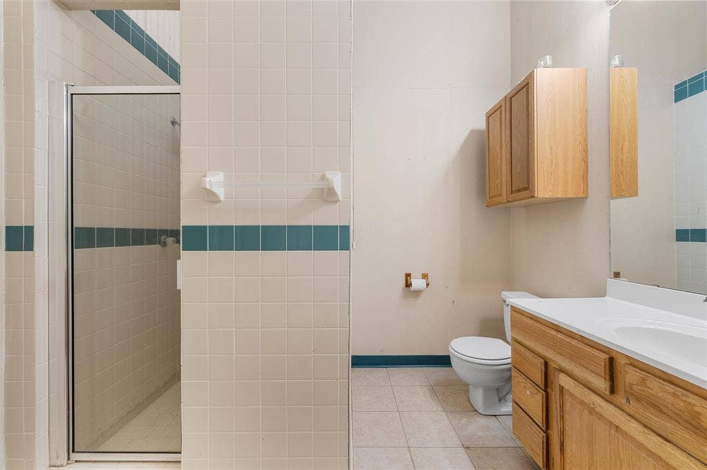 2029 Speegleville Road, Woodway, TX 76712 Shower with glass enclosure, single vanity with wood-finish cabinetry, built-in medicine cabinet, and tile flooring