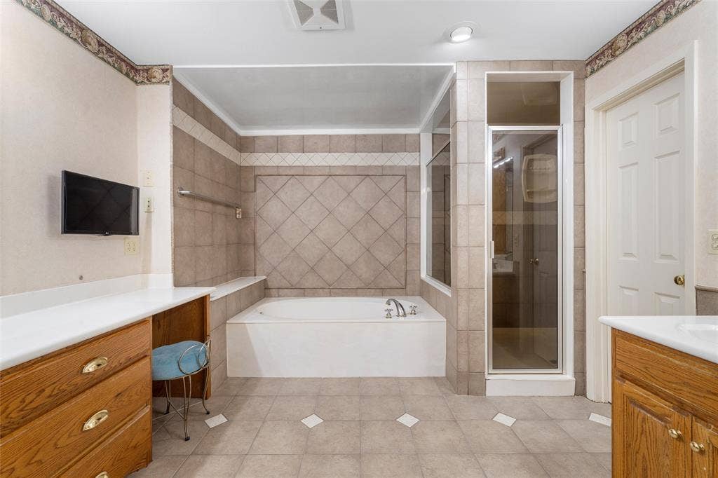 2029 Speegleville Road, Woodway, TX 76712 Ceramic tile flooring, tiled shower with glass enclosure, built-in bathtub, wood-finish vanity with countertop, and recessed lighting