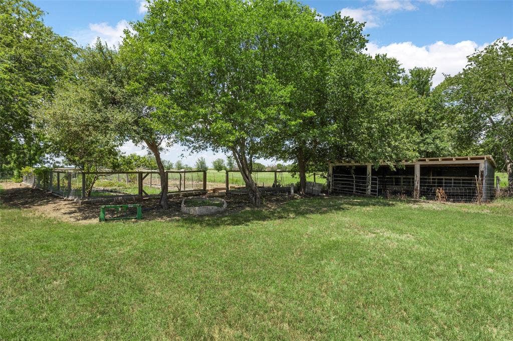 2029 Speegleville Road, Woodway, TX 76712 Expansive grassy area with mature trees, fenced enclosures, and a multi-stall shed structure