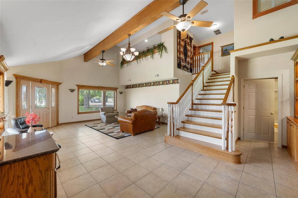 2029 Speegleville Road, Woodway, TX 76712 Vaulted ceilings with exposed wood beams, tile flooring, wood-finish staircase with white risers and balusters, and a decorative front entry door with sidelights