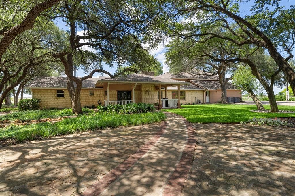 2029 Speegleville Road, Woodway, TX 76712 Brick exterior with a covered porch, white railing, and mature trees