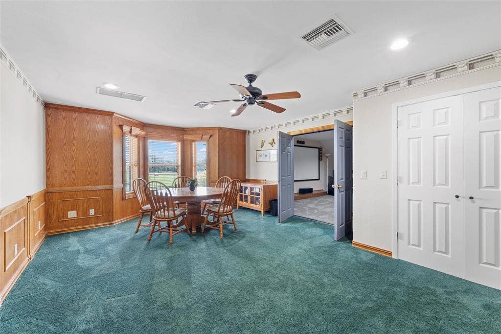 2029 Speegleville Road, Woodway, TX 76712 Bay window with exterior views, wood paneling, ceiling fan, carpet flooring, and double bi-fold doors