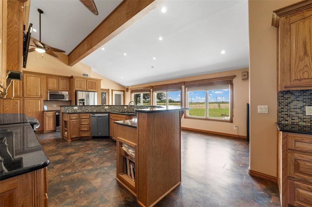 2029 Speegleville Road, Woodway, TX 76712 Spacious kitchen featuring wood cabinetry, dark countertops, built-in stainless steel appliances, and a vaulted ceiling with exposed beams