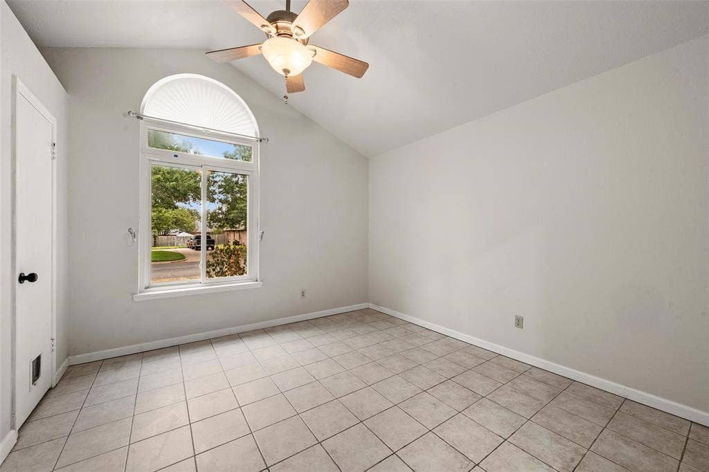 812 Regina Drive, Hewitt, TX 76643 Vaulted ceiling with an attached ceiling fan and light fixture, large arched window, tiled flooring, and a white paneled door