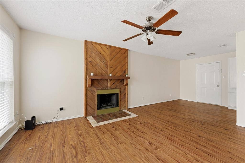 401 N 7th Street, #C, Midlothian, TX 76065 Wood-finish flooring, wood-paneled fireplace, built-in fireplace mantel, ceiling fan with integrated lighting, and a white entrance door