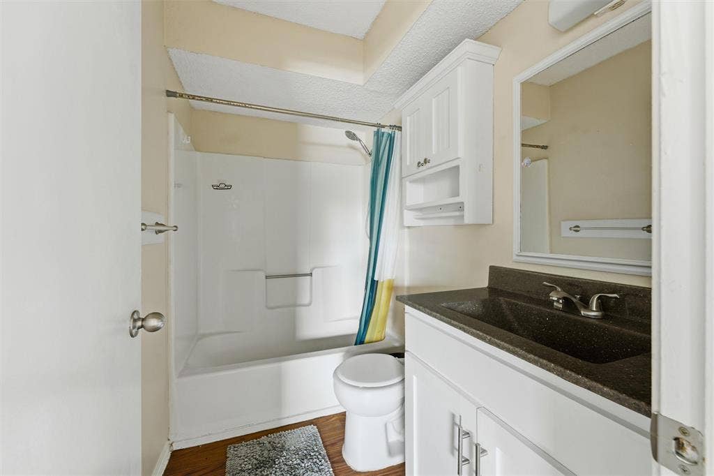 401 N 7th Street, #C, Midlothian, TX 76065 Bathroom featuring a white vanity with a dark countertop, an integrated sink, a white medicine cabinet, and a white tub/shower combination