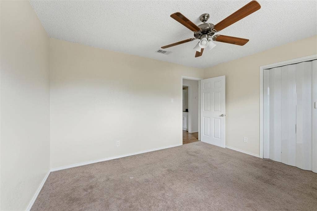 401 N 7th Street, #C, Midlothian, TX 76065 Neutral-toned walls, carpeted flooring, ceiling fan with integrated lighting, paneled door, and bi-fold closet doors
