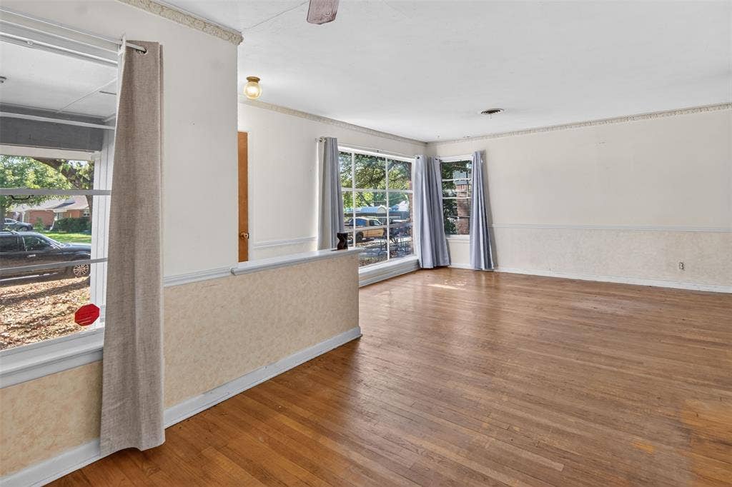 2024 Blake Avenue, Dallas, TX 75228 Hardwood flooring throughout, multiple large windows, cased openings, crown molding, and a partial wall with textured detailing
