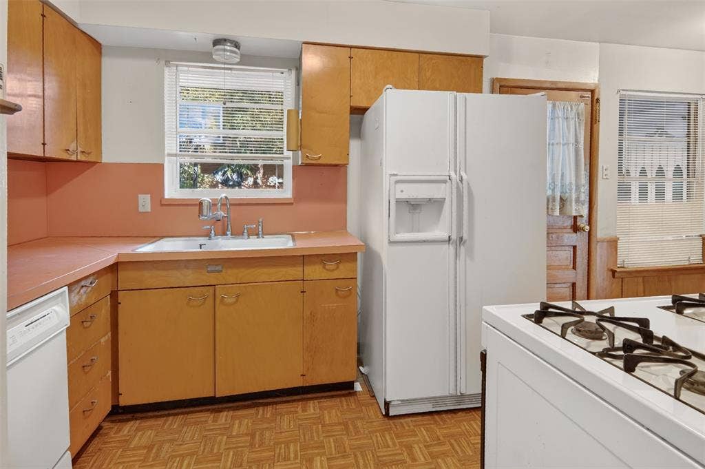 2024 Blake Avenue, Dallas, TX 75228 L-shaped kitchen with wood-finish cabinetry, a white double-door refrigerator, and a white gas range