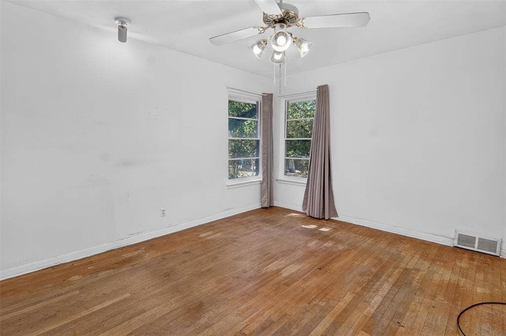 2024 Blake Avenue, Dallas, TX 75228 Hardwood flooring, two windows, ceiling fan, white walls, and a wall-mounted light fixture