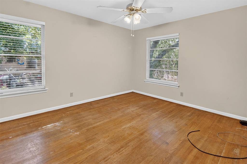 2024 Blake Avenue, Dallas, TX 75228 Wood-finish flooring, two windows with blinds, and a ceiling fan with integrated lighting