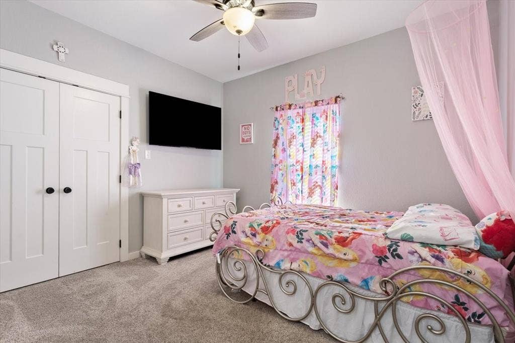 10305 Creekside Lane, Waco, TX 76712 Textured gray carpeting, light gray wall paint, white bi-fold closet doors with black hardware, and a ceiling fan with integrated lighting