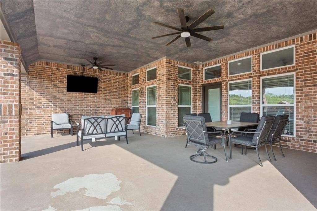 10305 Creekside Lane, Waco, TX 76712 Covered outdoor living space featuring brick walls, concrete flooring, and multiple ceiling fans