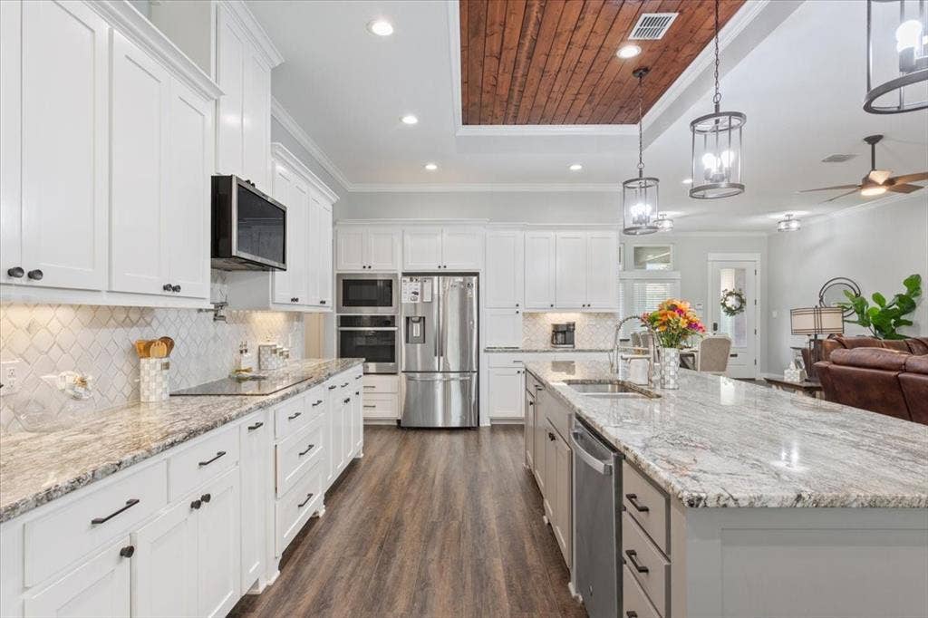 10305 Creekside Lane, Waco, TX 76712 Expansive kitchen featuring white cabinetry, light-toned countertops, stainless steel appliances, wood-finish flooring, and a coffered wood ceiling detail