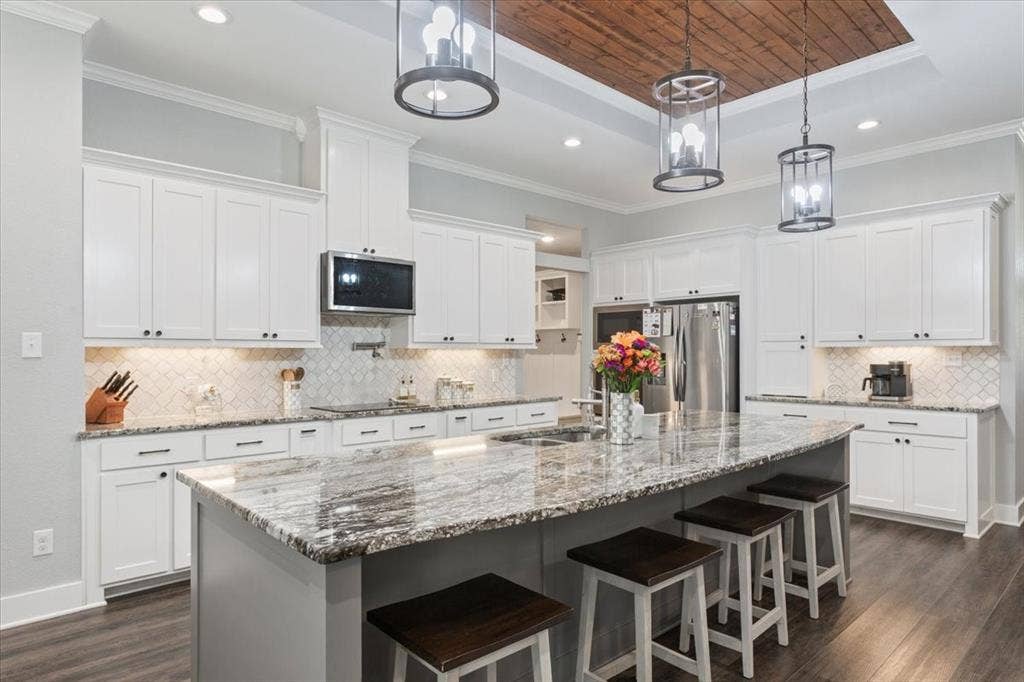 10305 Creekside Lane, Waco, TX 76712 Spacious kitchen featuring white cabinetry, a large center island with a stone countertop, a tile backsplash, and wood-finish flooring